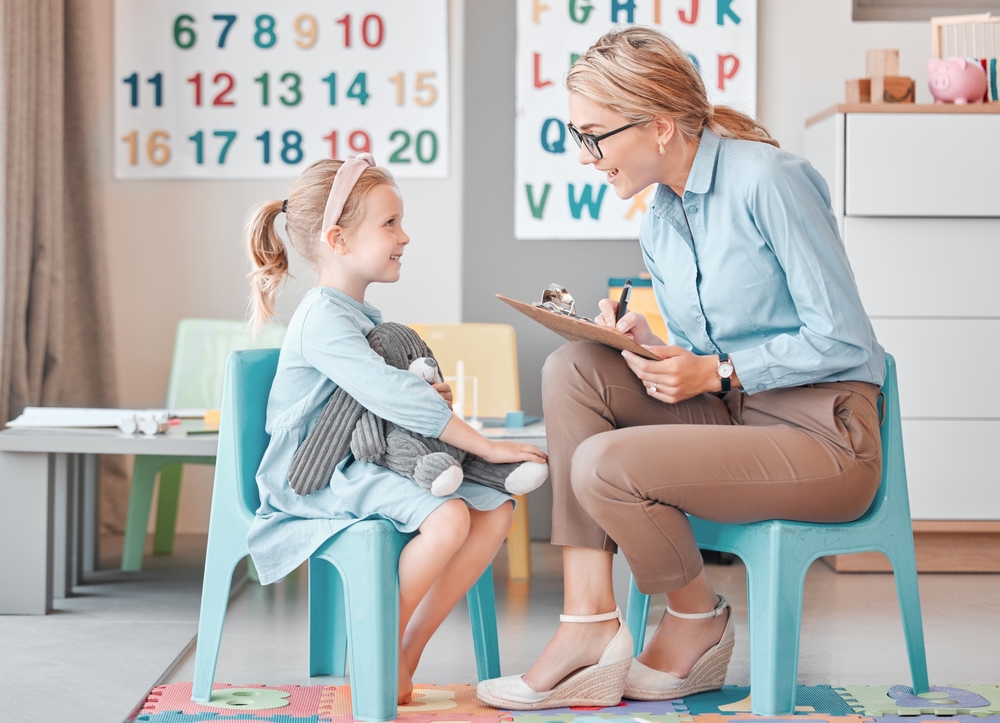 Child psychologist speaking with young girl holding stuffed toy at Child Expert Network consultation